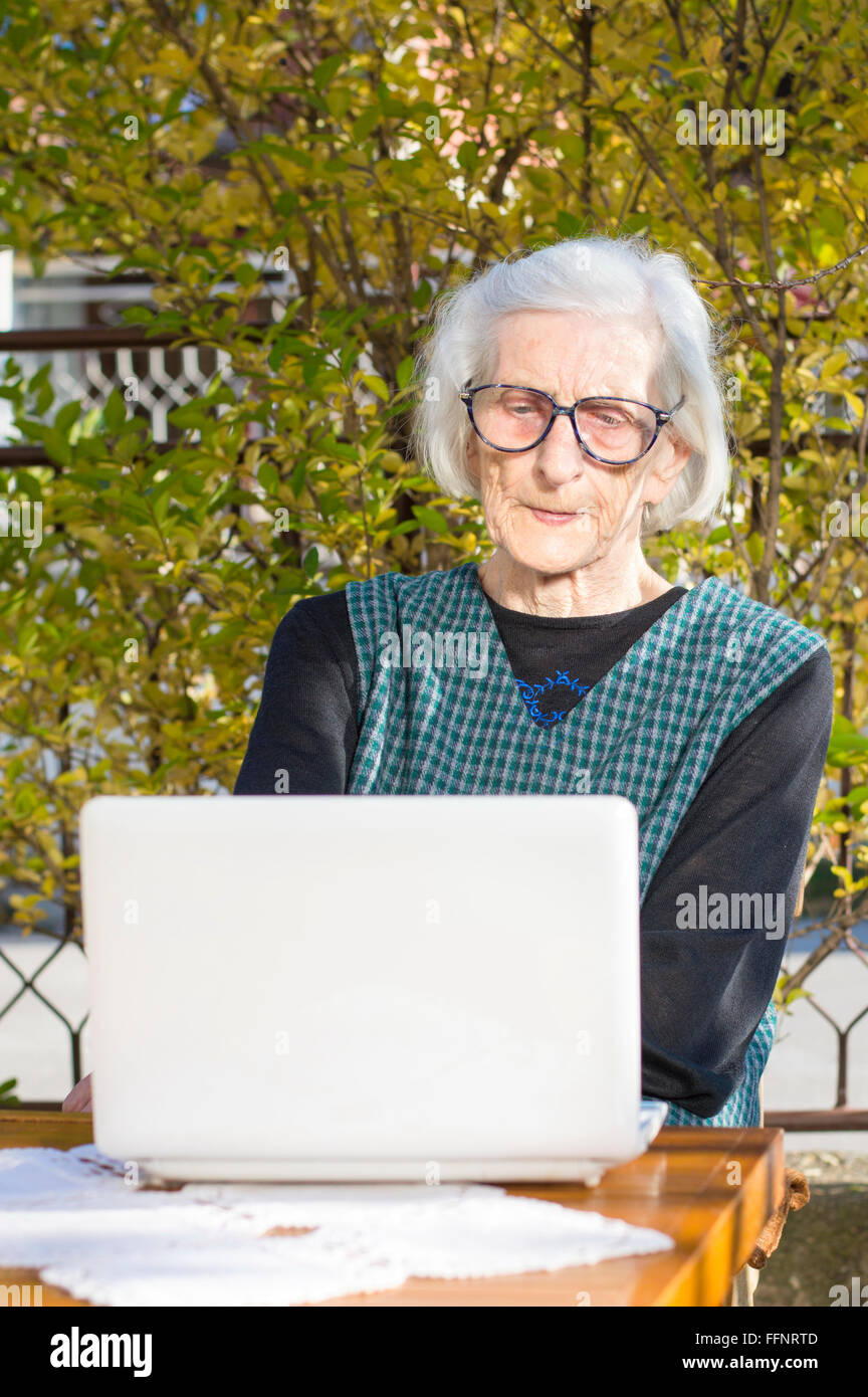 Femme de 90 ans ayant un appel vidéo sur un ordinateur portable blanc Banque D'Images