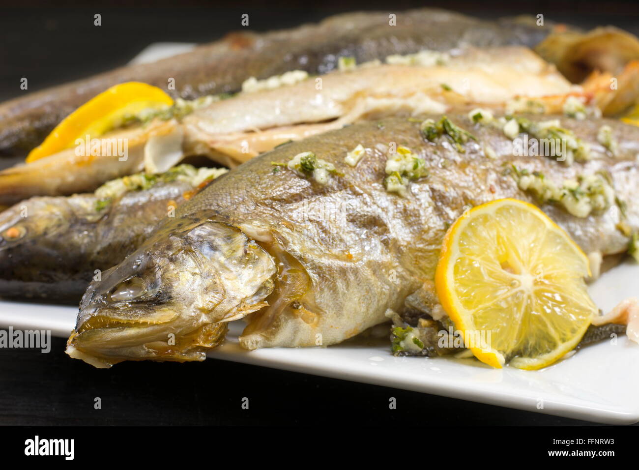 Truite au four poisson servi sur une assiette avec du citron et des épices Banque D'Images