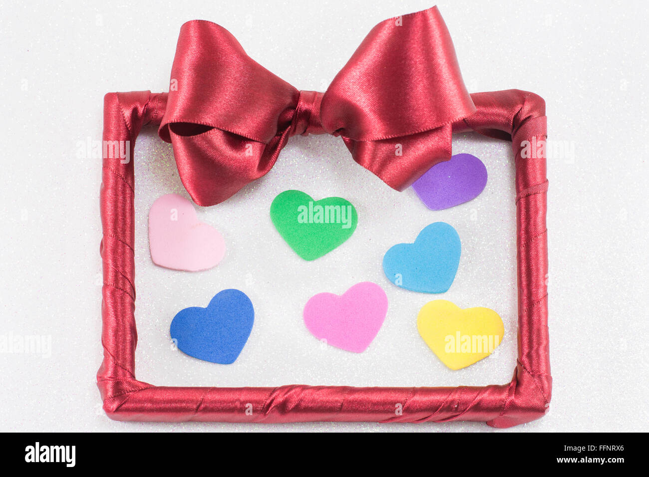 Cadre photo vide avec ruban rouge avec des coeurs colorés sur fond blanc Banque D'Images