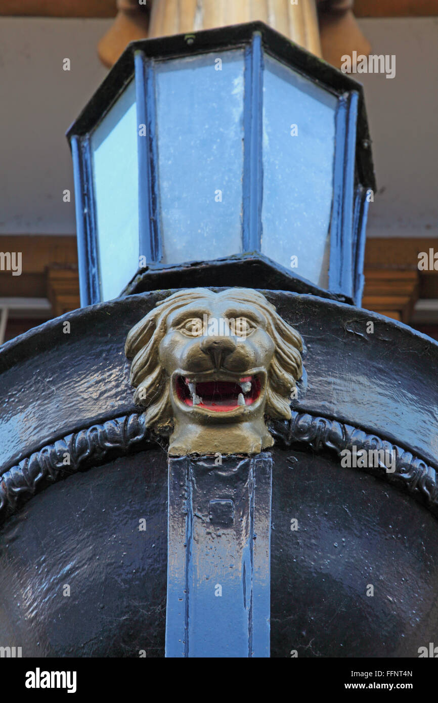 Or une fonte peinte avec quatre Lions Head rugueux blanc à dents dans sa bouche ouverte monté juste en dessous d'un grand verre lampe. Banque D'Images
