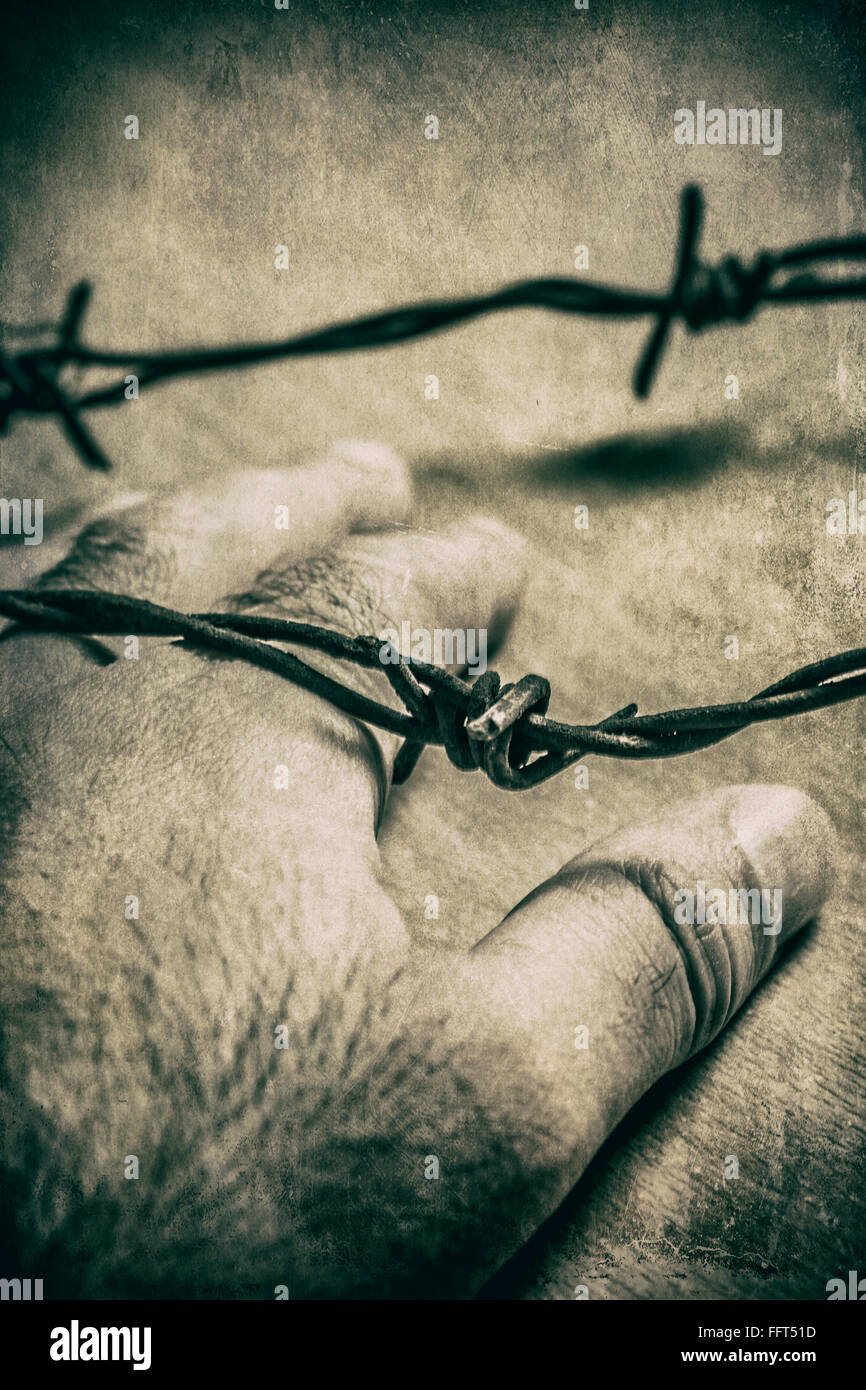 La main de l'homme dans le cadre d'un fil de fer barbelé Banque D'Images