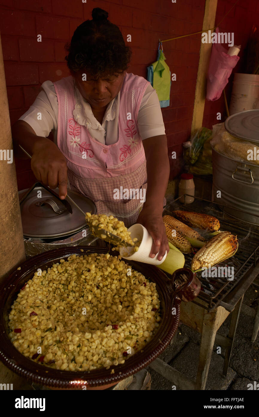 Femme mexicaine de maïs de friture et le remplit dans une tasse Banque D'Images