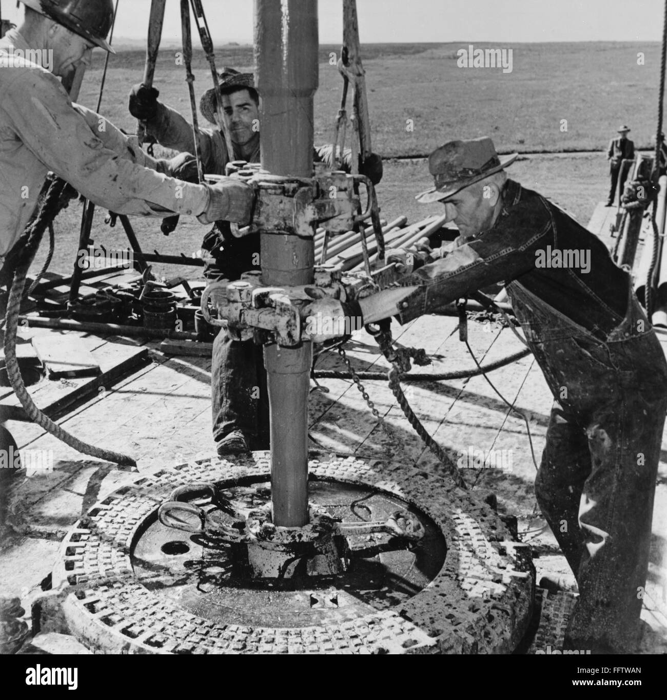 New York : PUITS DE PÉTROLE, c1944. /N'Wildcat' foreurs de pétrole d'une  compagnie pétrolière indépendante, à l'aide d'outils appelés 'tongs' qui  sont fixées sur la perceuse pour dévisser la tige, section par