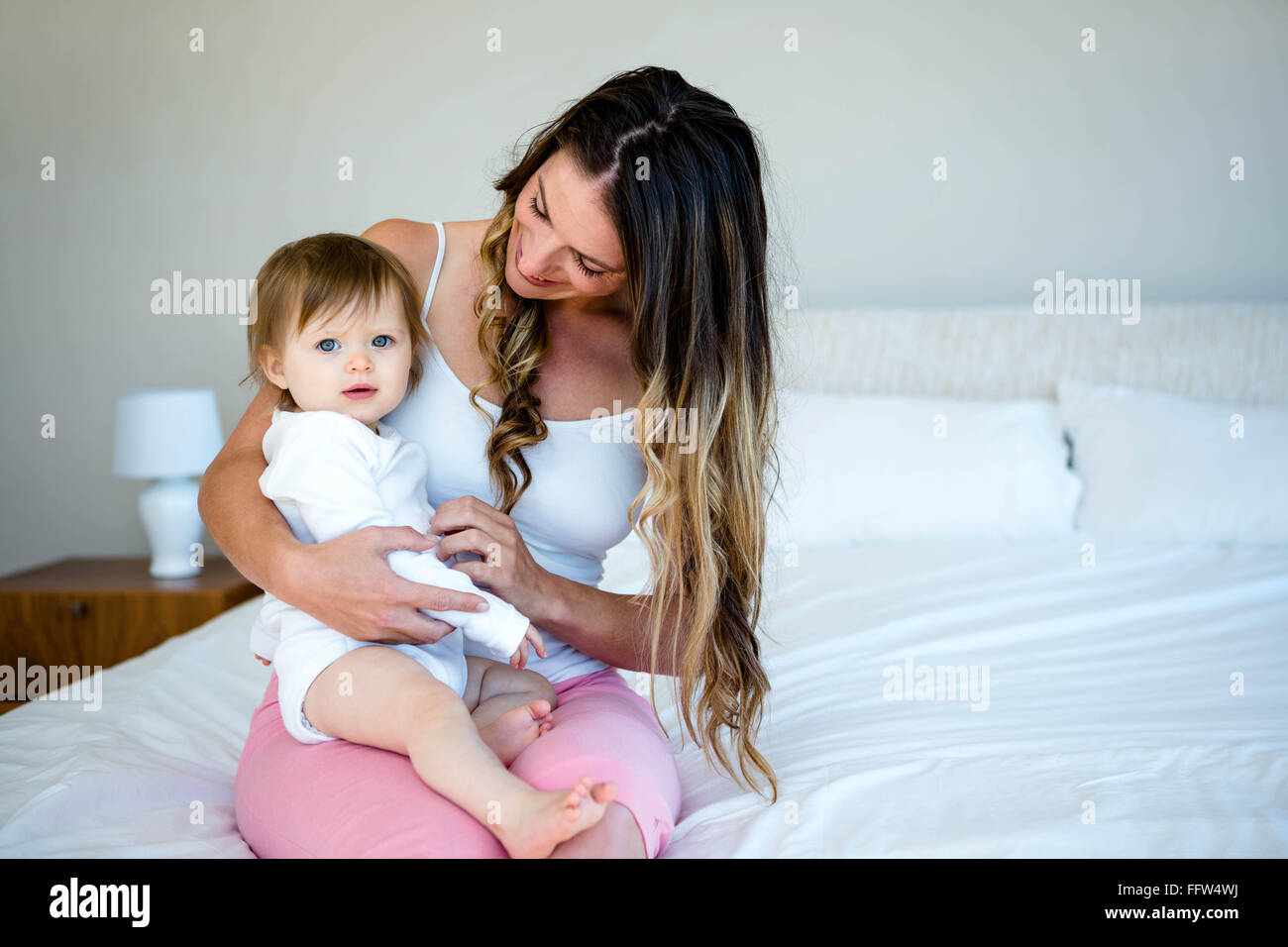 Brunette woman holding a baby sur un lit Banque D'Images