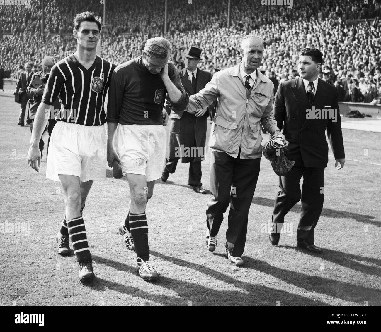 BERT TRAUTMANN (1923- ). /NGerman-joueur de football anglais né à Manchester City. Trautmann (centre gauche), après avoir joué les dernières minutes de la partie avec une blessure au cou, laissant le terrain après la victoire de Manchester Birmingham City en finale de la coupe d'ANGLETERRE Banque D'Images