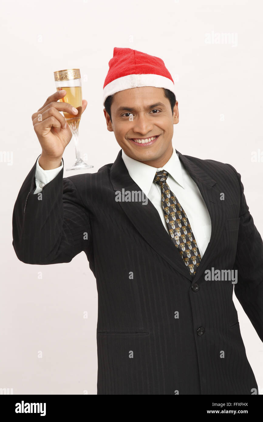 Businessman wearing Santa Clause cap a soulevé un verre de vin dans la main droite M.# 703T Banque D'Images