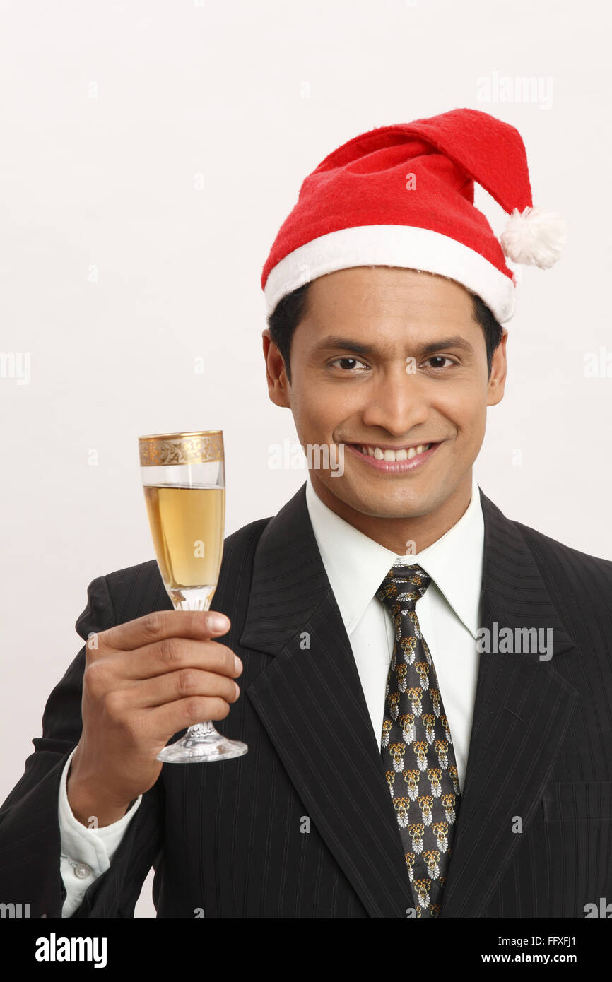 Businessman wearing Santa Clause cap a soulevé un verre de vin dans la main droite M.# 703T Banque D'Images