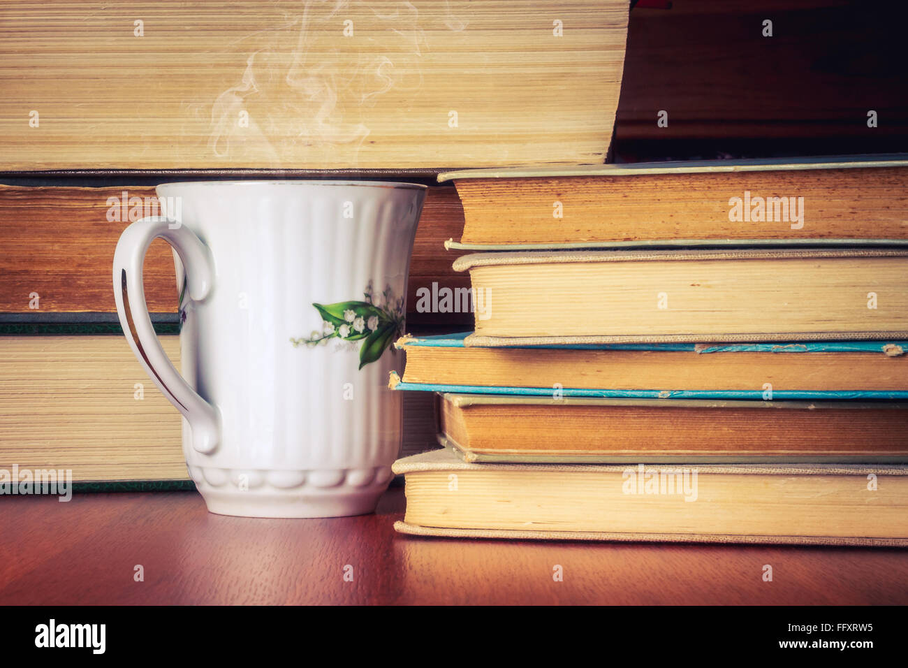Tasse de thé debout à côté de la pile de livres anciens Banque D'Images