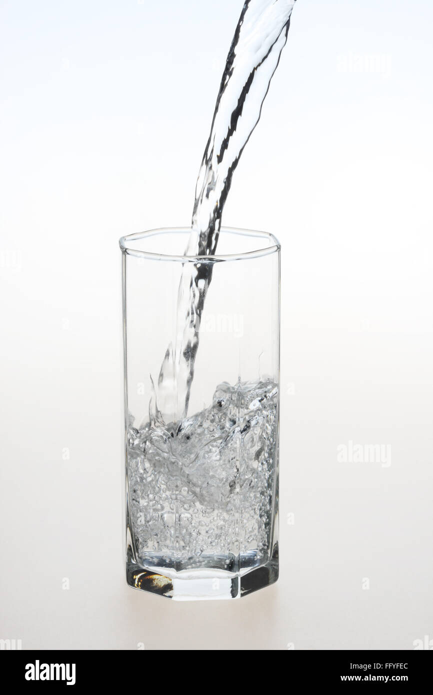 Verser de l'eau dans du verre transparent sur fond blanc Banque D'Images