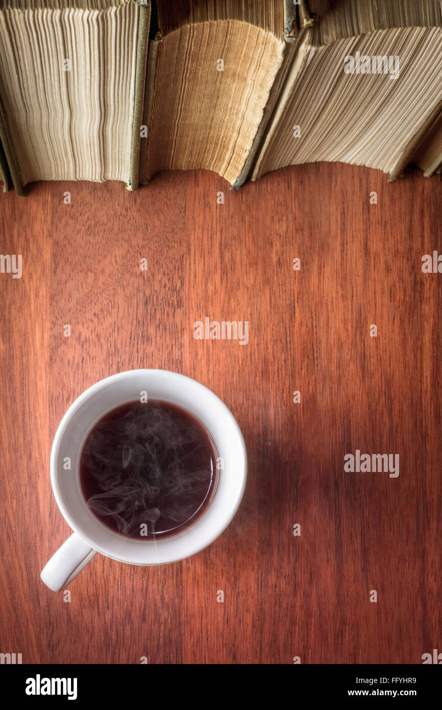 Tasse de café debout à côté de la pile de livres anciens Banque D'Images