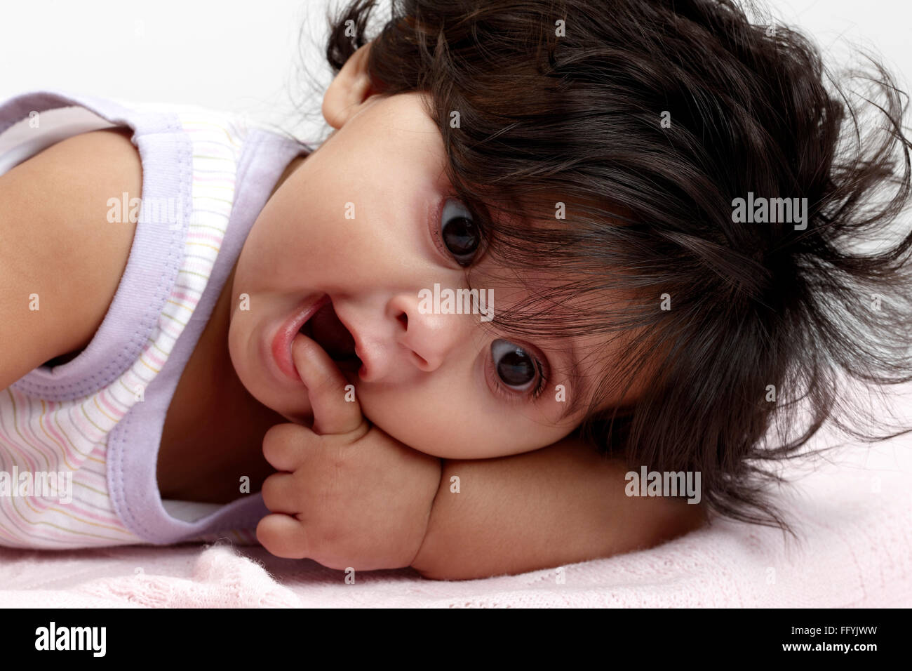 Robe bébé fille joyeuse à se coucher mettre doigt dans bouche M.# 765 Banque D'Images