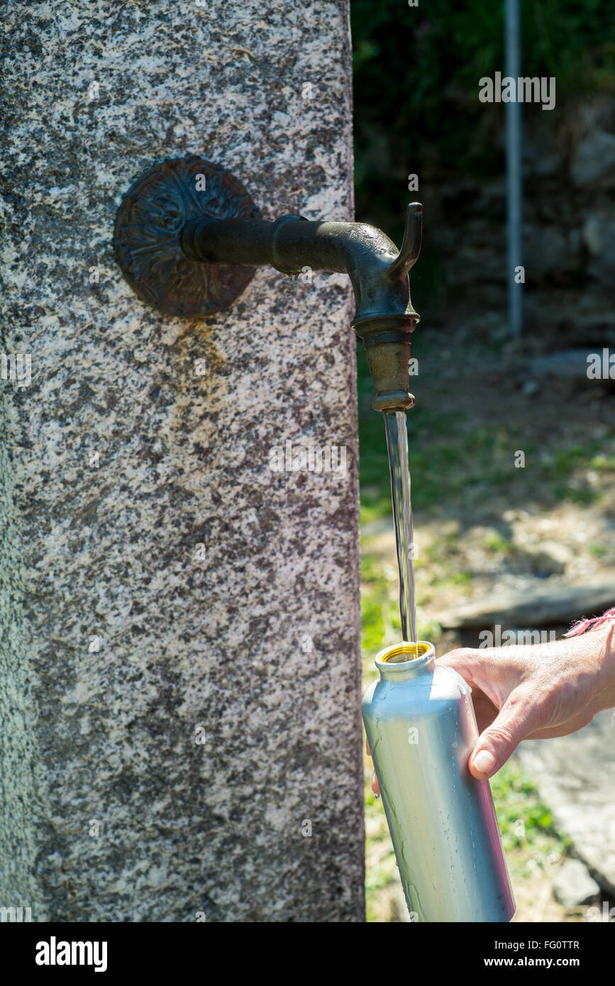 La collecte de l'eau fraîche à la fontaine dans la Val Grande réserve intégrale, Alpes Italiennes Banque D'Images