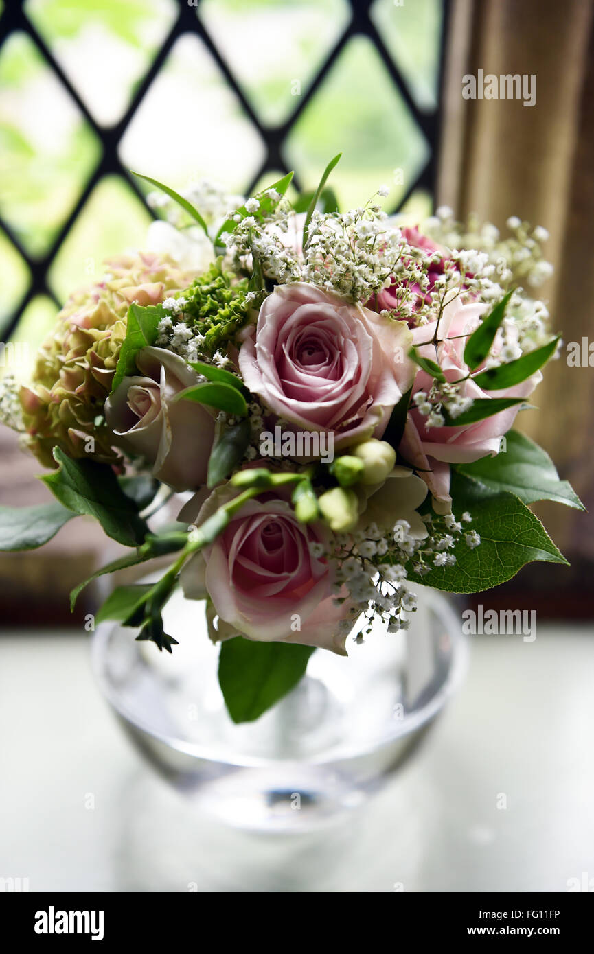 Un joli bouquet de roses roses dans un petit vase à un mariage Banque D'Images