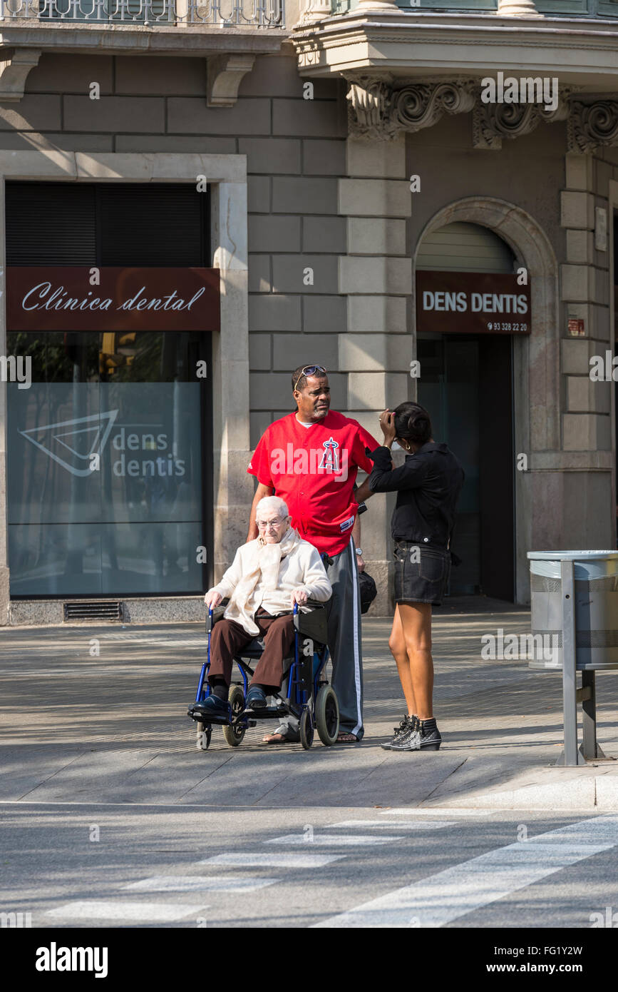 Vieille Femme dans un fauteuil roulant avec son aidant marcher dans les rues de Barcelone, Catalogne, Espagne Banque D'Images