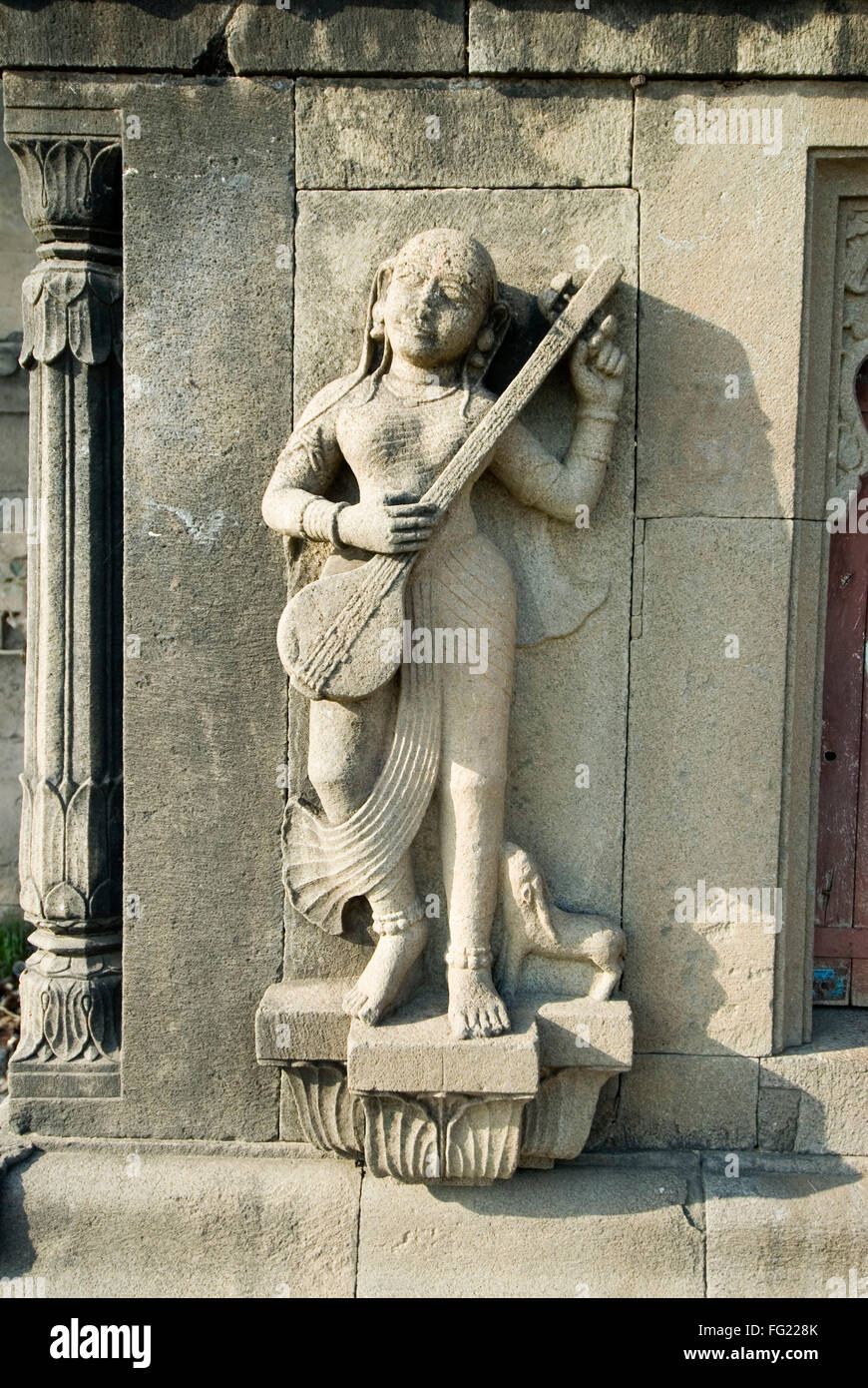 Femme avec des instruments de musique de tambora sculpté dans la pierre sur le mur de Maheshwar Maheshwar , temple , Madhya Pradesh, Inde Banque D'Images