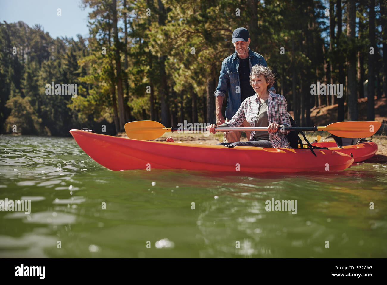 Portrait of mature man giving instructions to woman paddling kayak dans le lac. Senior woman getting kayak leçons d'un ma Banque D'Images