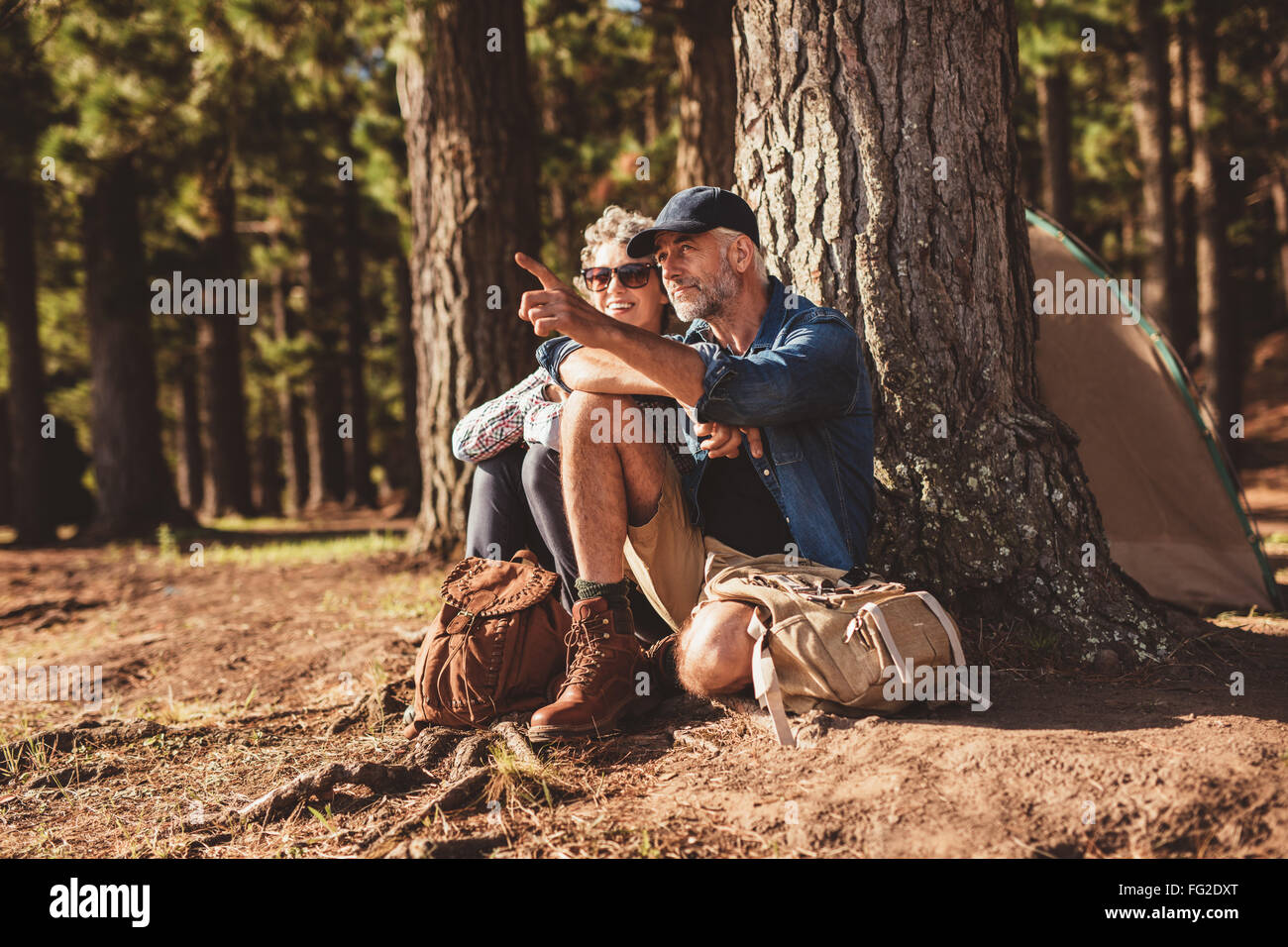 Portrait of mature couple relaxing at leur camping avec l'homme montrant quelque chose à la femme. Senior couple Randonnée et camping au fo Banque D'Images