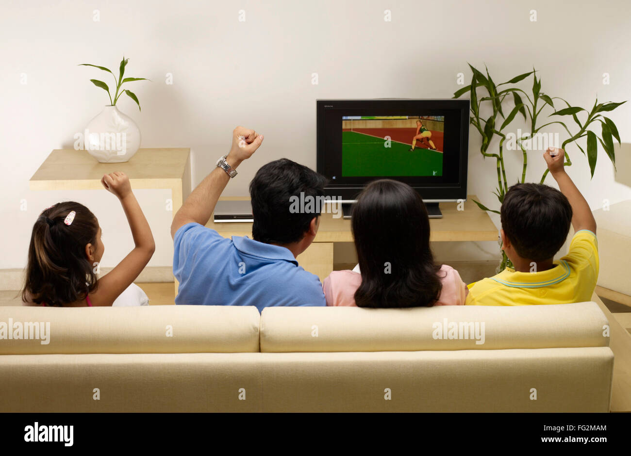 Les enfants avec des parents qui applaudissent au match à la télévision assis à la maison MR#702R,MR#702S,MR#702T,MR#702U Banque D'Images