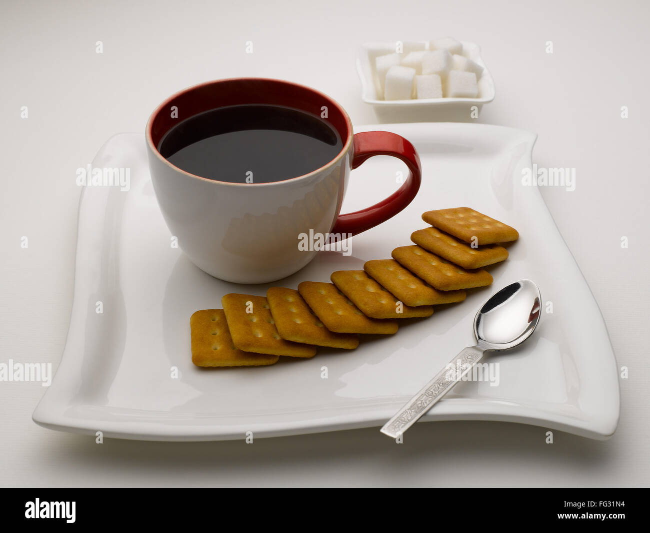 Tasse de thé noir en plat de service avec des morceaux de sucre et de biscuits en Inde Banque D'Images