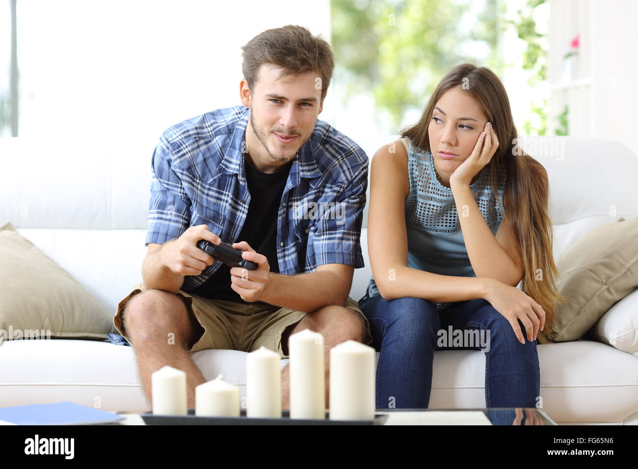 L'homme jouant des jeux vidéo à la maison et sa petite amie s'ennuyer à côté de le regarder Banque D'Images