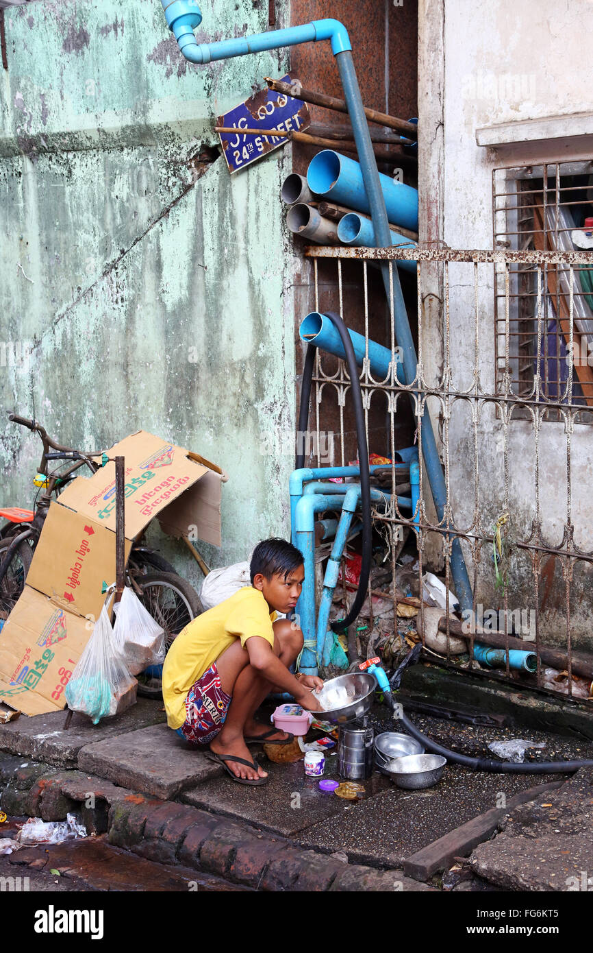 Garçon laver la vaisselle dans la Rue, Yangon, Myanmar Banque D'Images