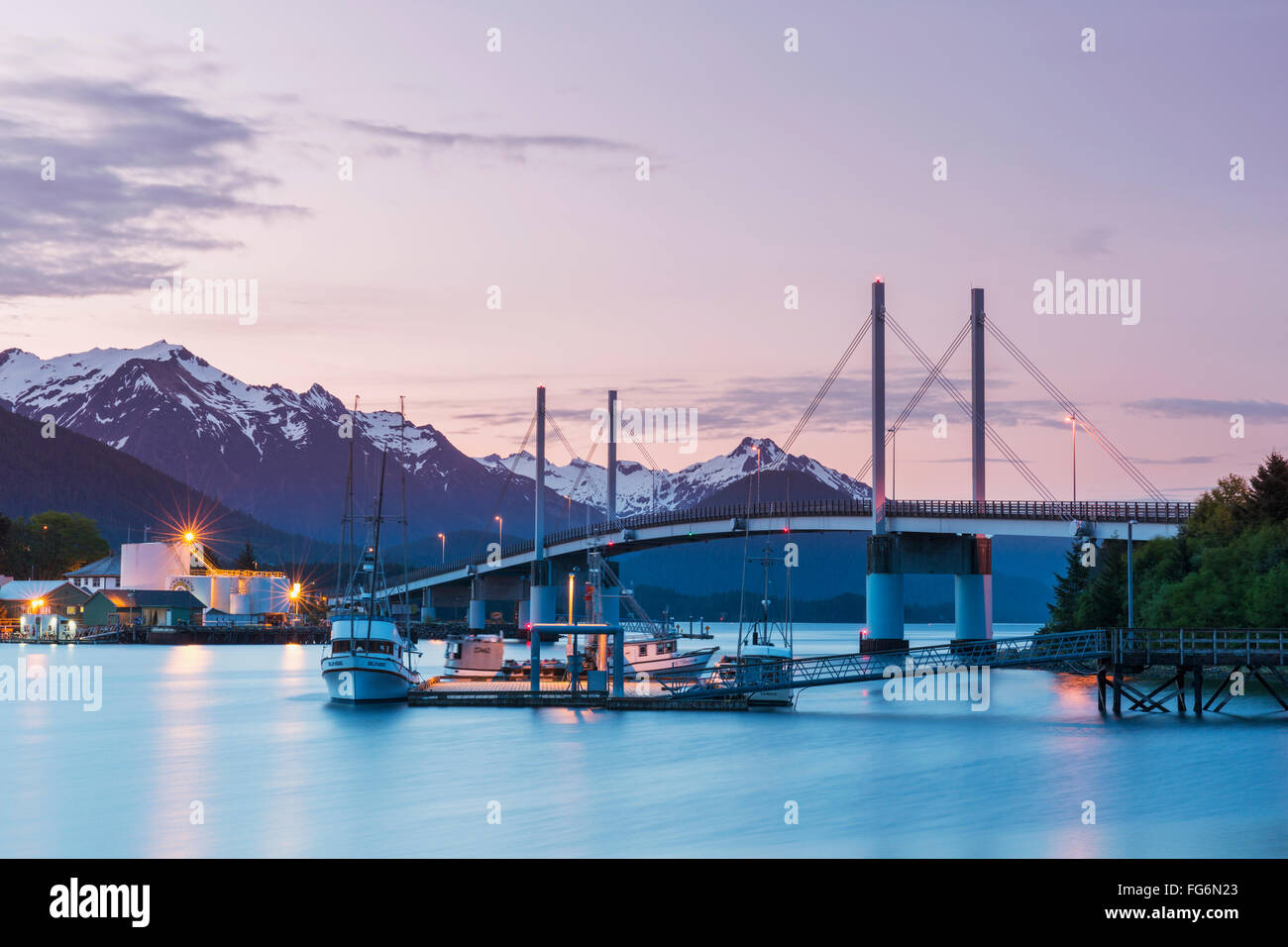 Bateau de pêche amarré le long de la jetée dans le port de Sitka avec le pont O'connell et les montagnes en arrière-plan à Twilight, sud-est de l'Alaska, USA, su... Banque D'Images
