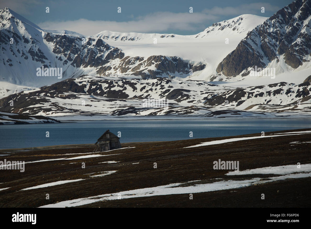 Petit chalet en bois sur la rive de l'océan Arctique et des montagnes enneigées, Spitsbergen, Svalbard, Norvège Banque D'Images