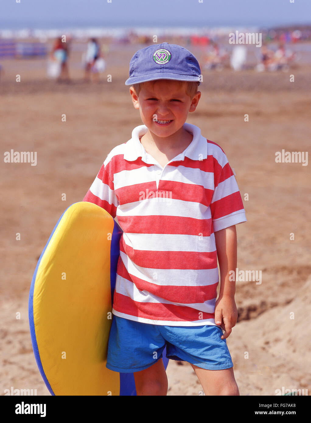 Young boy holding surfboard on beach, Bude, Devon, Angleterre, Royaume-Uni Banque D'Images