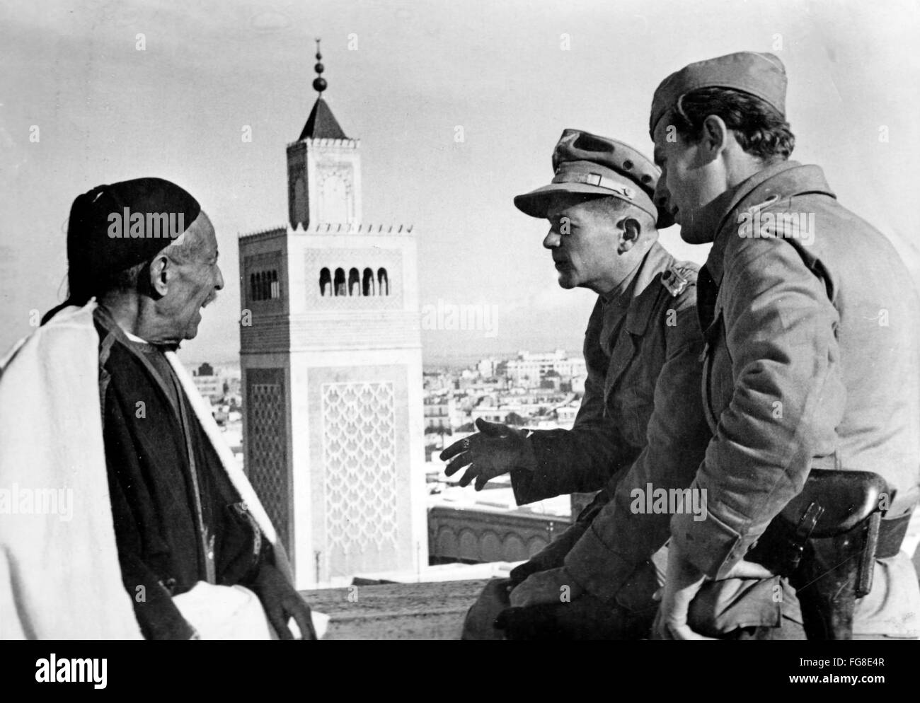 Le tableau de la propagande nazie montre deux soldats de la Wehrmacht allemande discutant avec un local en face de la mosquée Ez-Zitouna dans la ville occupée de Tunis en Tunisie. La photo a été prise en mars 1943. Fotoarchiv für Zeitgeschichtee - PAS DE SERVICE DE VIREMENT - Banque D'Images