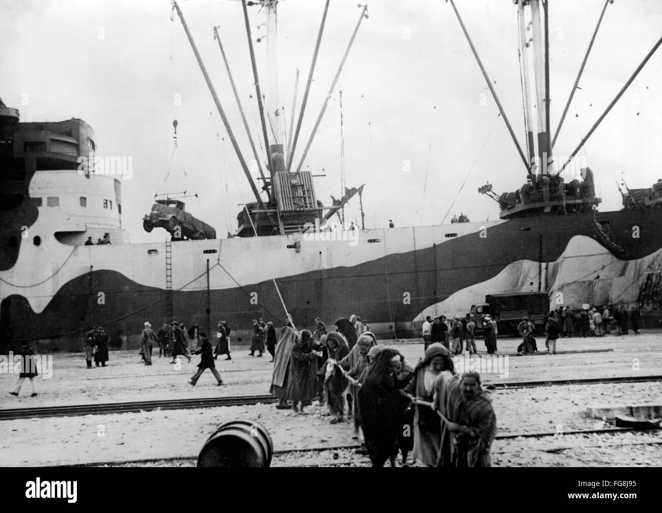 Le tableau de la propagande nazie montre comment les habitants chargent un véhicule à moteur de la Wehrmacht allemande dans la ville occupée de Tunis, en Tunisie. La photo a été publiée en février 1943. Fotoarchiv für Zeitgeschichtee - PAS DE SERVICE DE VIREMENT - Banque D'Images