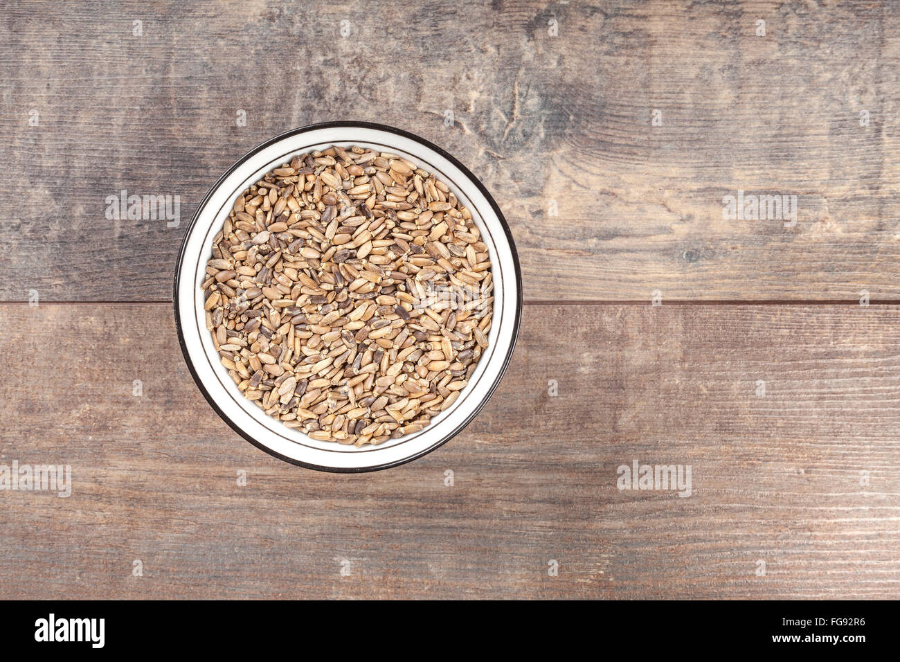 Graines d'un chardon de lait dans un bol sur fond de bois. Banque D'Images
