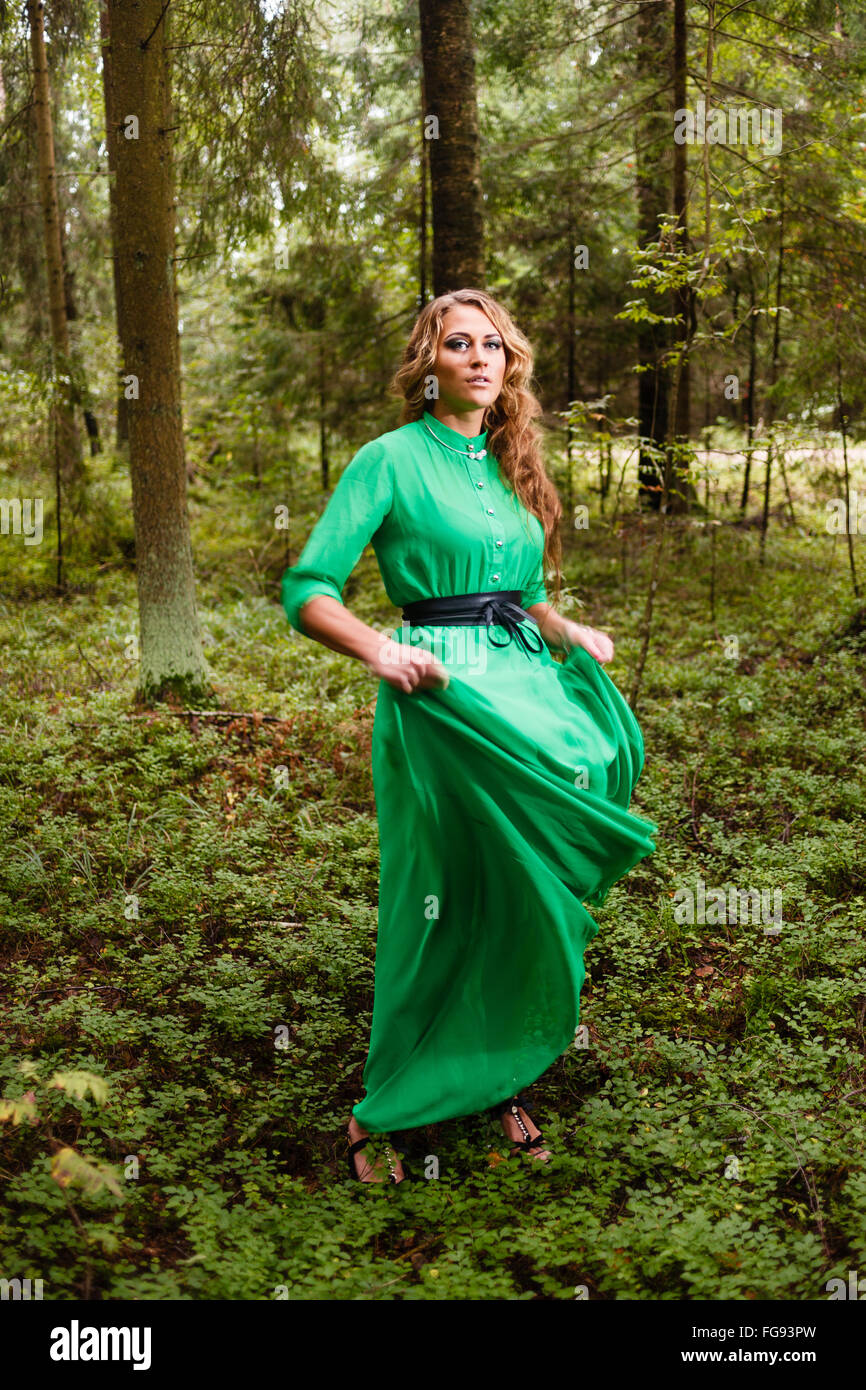 Long-hair girl en robe verte à la forêt. Banque D'Images