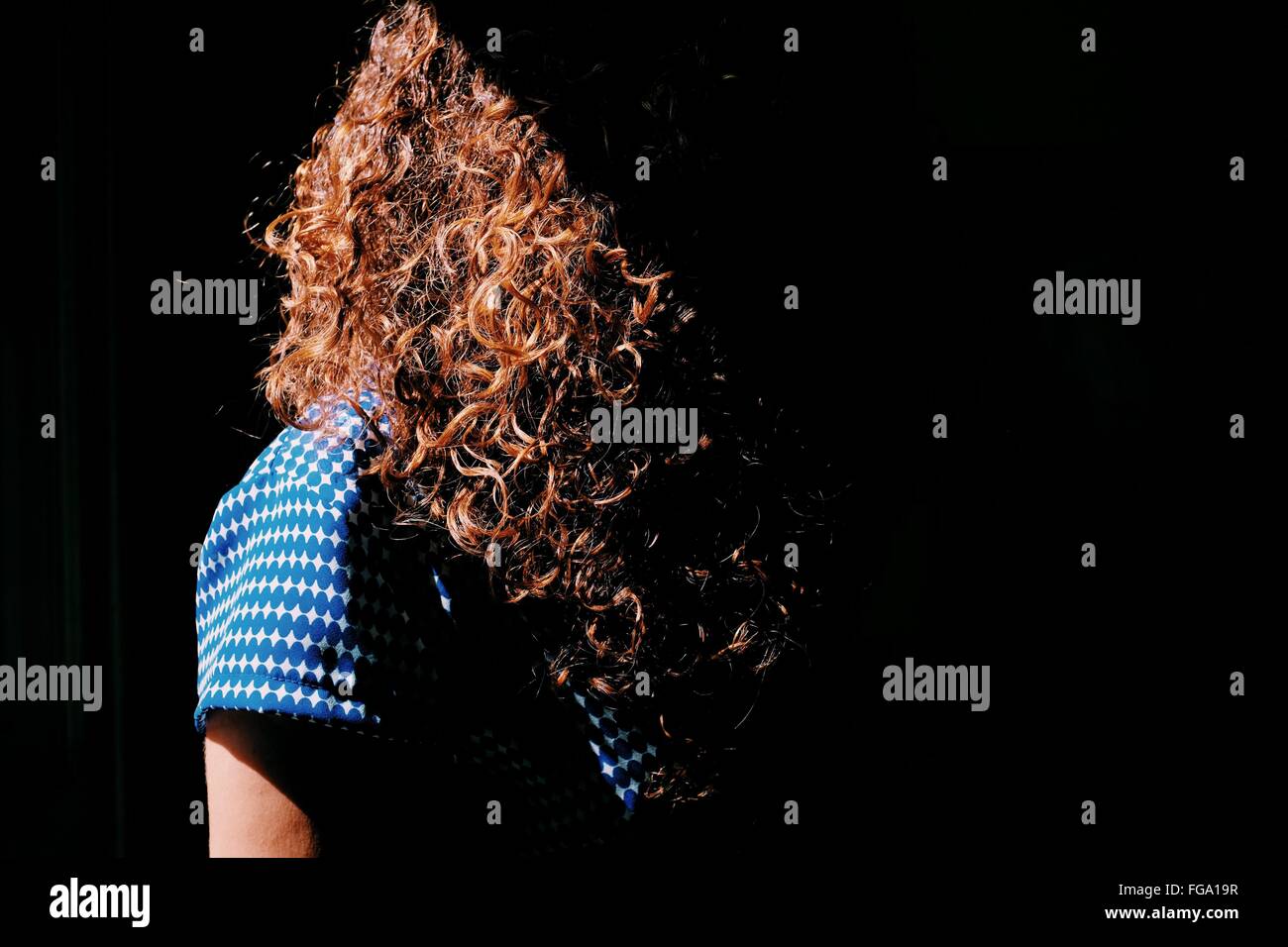 Femme aux cheveux bruns bouclés à la lumière du soleil Banque D'Images
