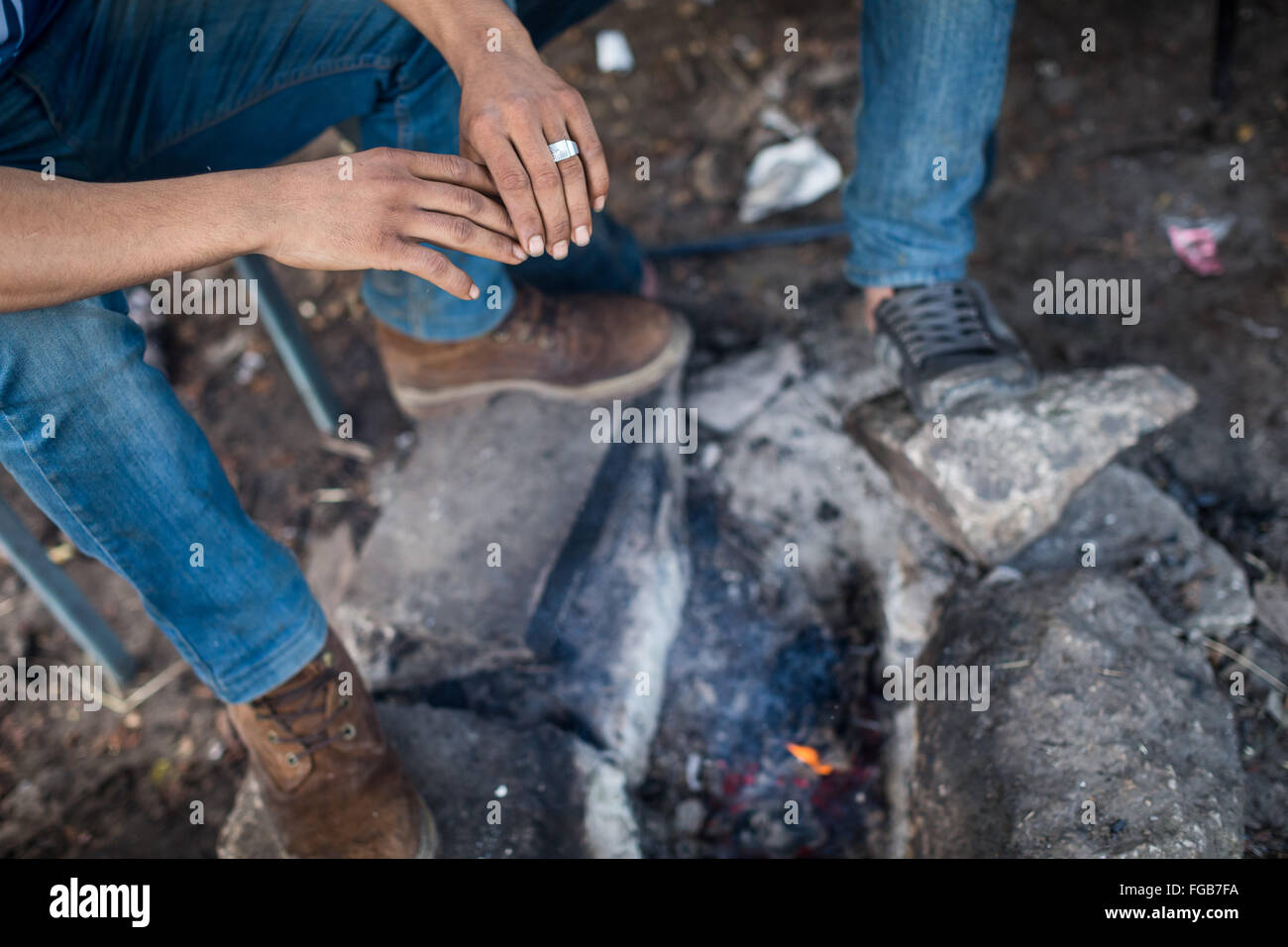 Les mains d'un réfugié kurde comme il se réchauffe-les sur un feu en sa tente dans le camp de réfugiés de la jungle à Calais. Banque D'Images