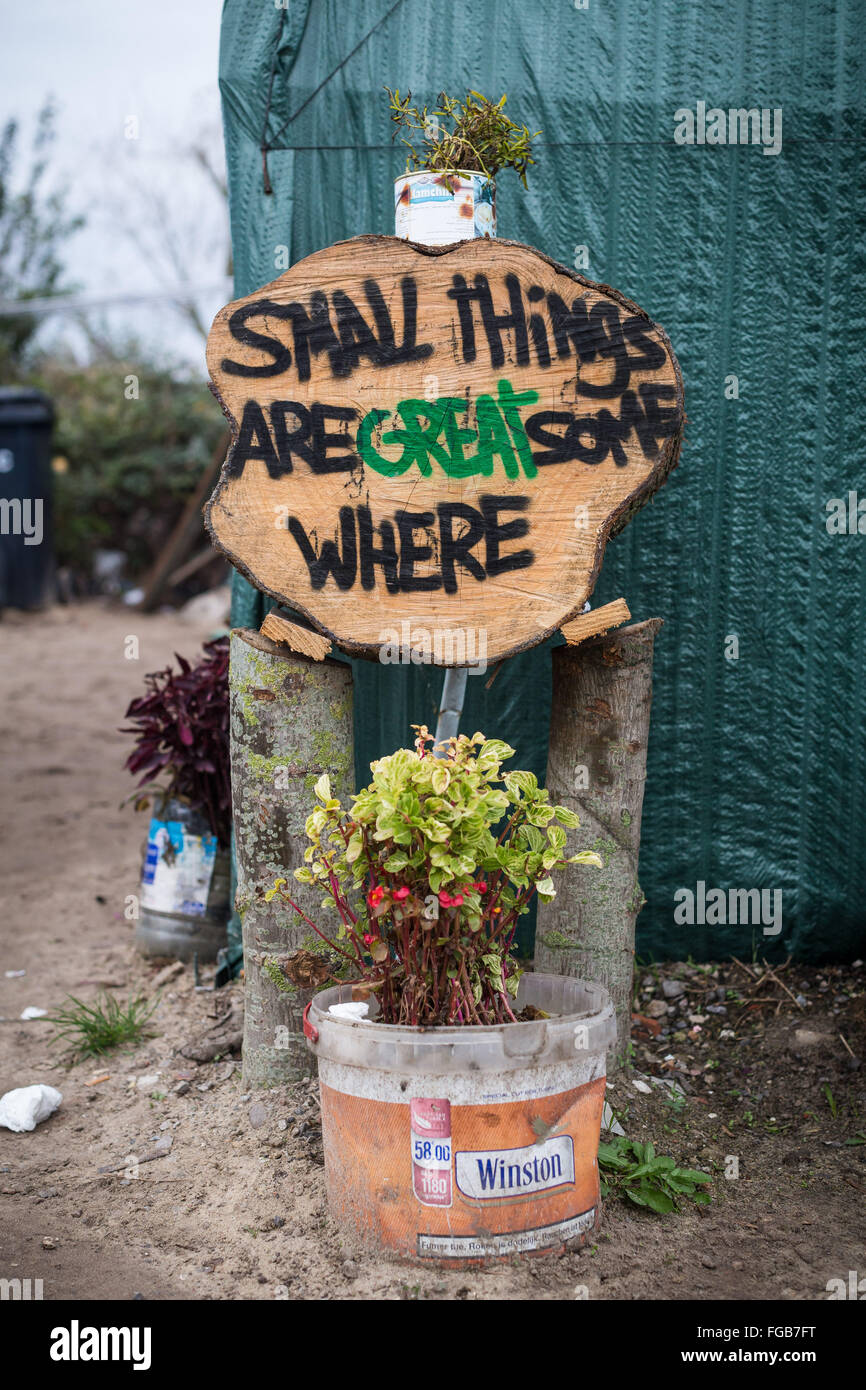 Un signe fait maison et de plantes en pot à l'extérieur un abri dans la jungle camp de réfugiés, Calais. Il lit des "petites choses sont grand quelque part". Banque D'Images