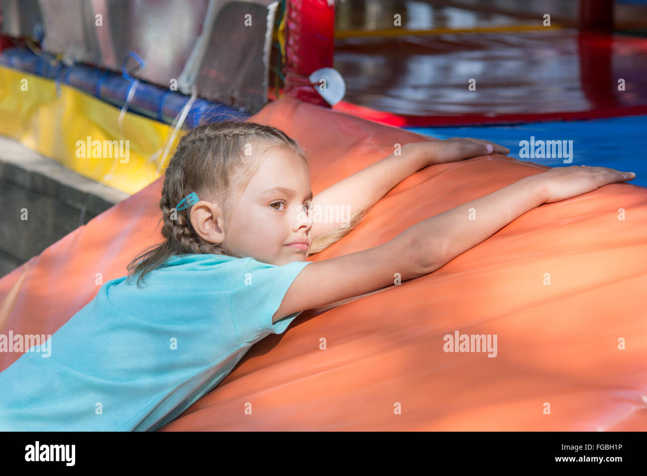 Fille de six ans se trouve sur un tapis mou en face de la chambre d'enfants de rue Banque D'Images