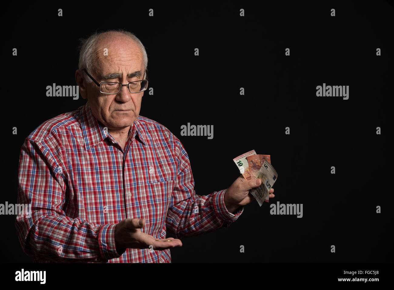 Vieil homme portant des lunettes et chemise à carreaux holding euro banknotes Banque D'Images