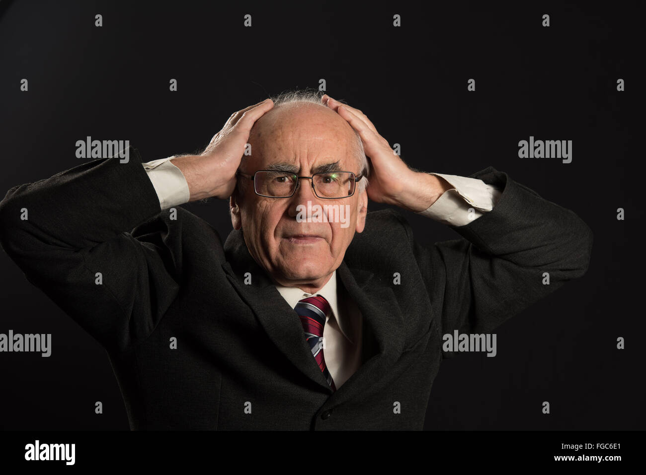 Senior businessman wearing eyeglasses sur fond noir souligné en difficulté Banque D'Images