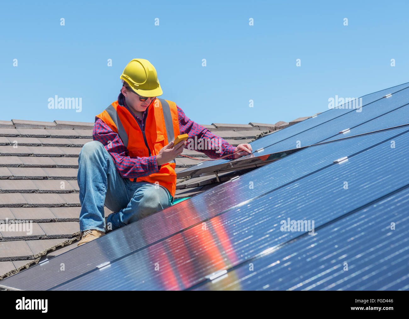 Jeune travailleur contrôle de panneaux solaires sur toit de maison Banque D'Images