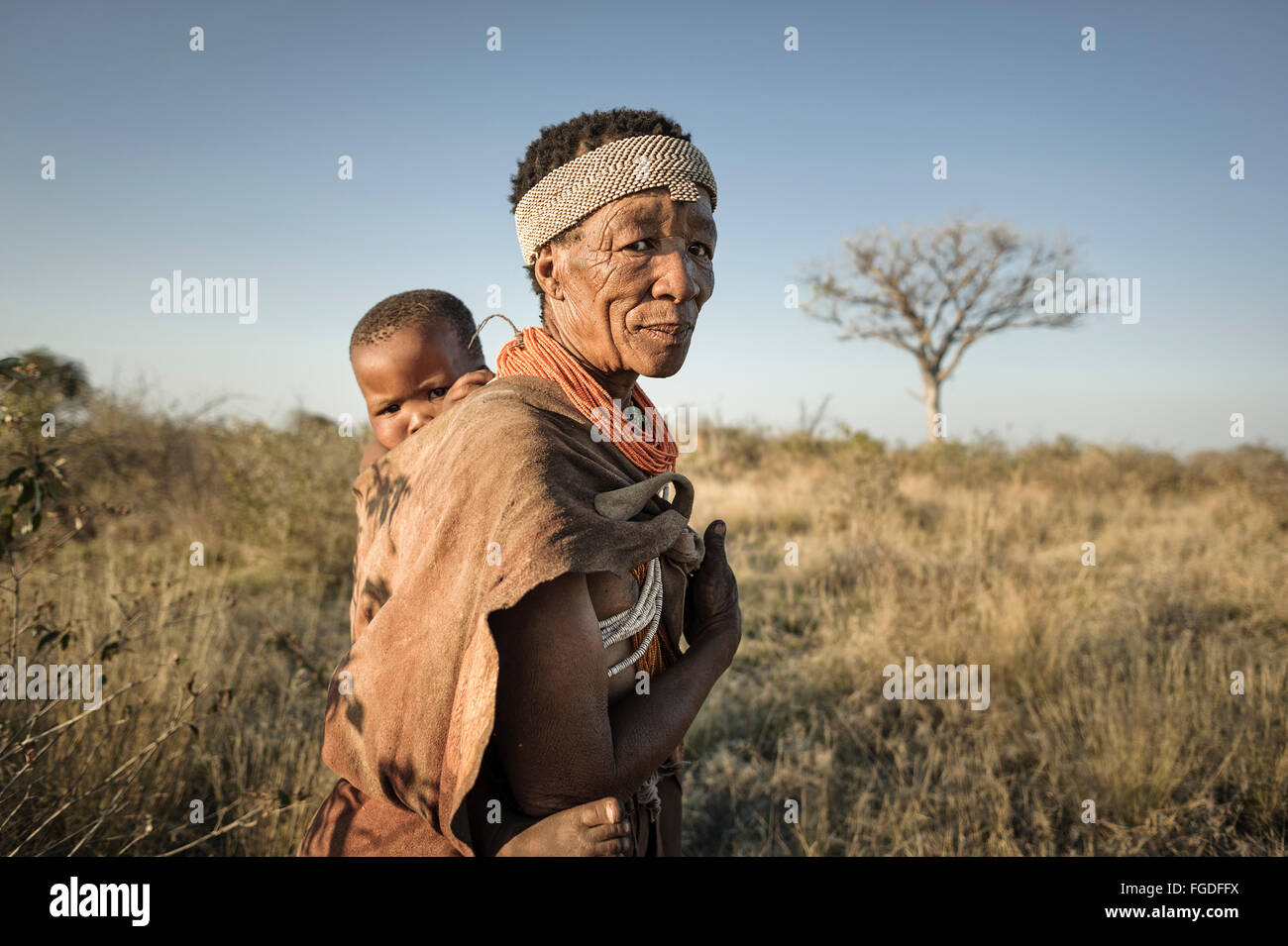 Femme Bushmen exerçant son enfant à son retour Banque D'Images