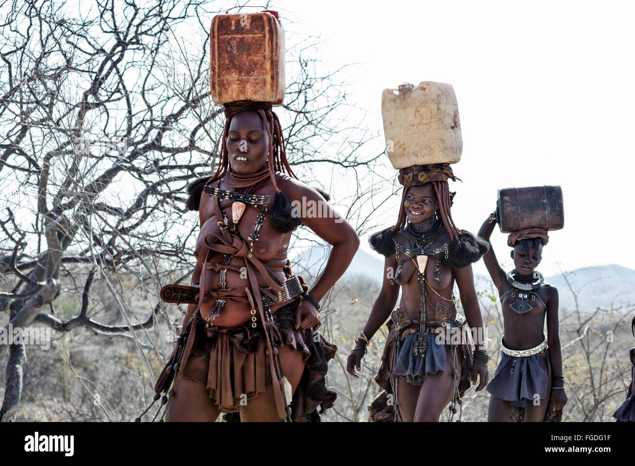 Les femmes Himba transportant des conteneurs en plastique plein d'eau sur la tête. Banque D'Images