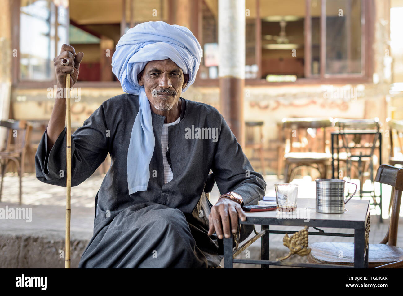 Portrait d'un homme avec anneau typique turban et boire le thé dans un petit bar terrasse. Banque D'Images