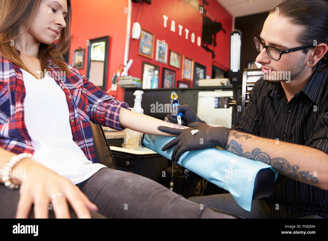 Woman Sitting in Chair ayant Tattoo sur le bras dans le salon Banque D'Images