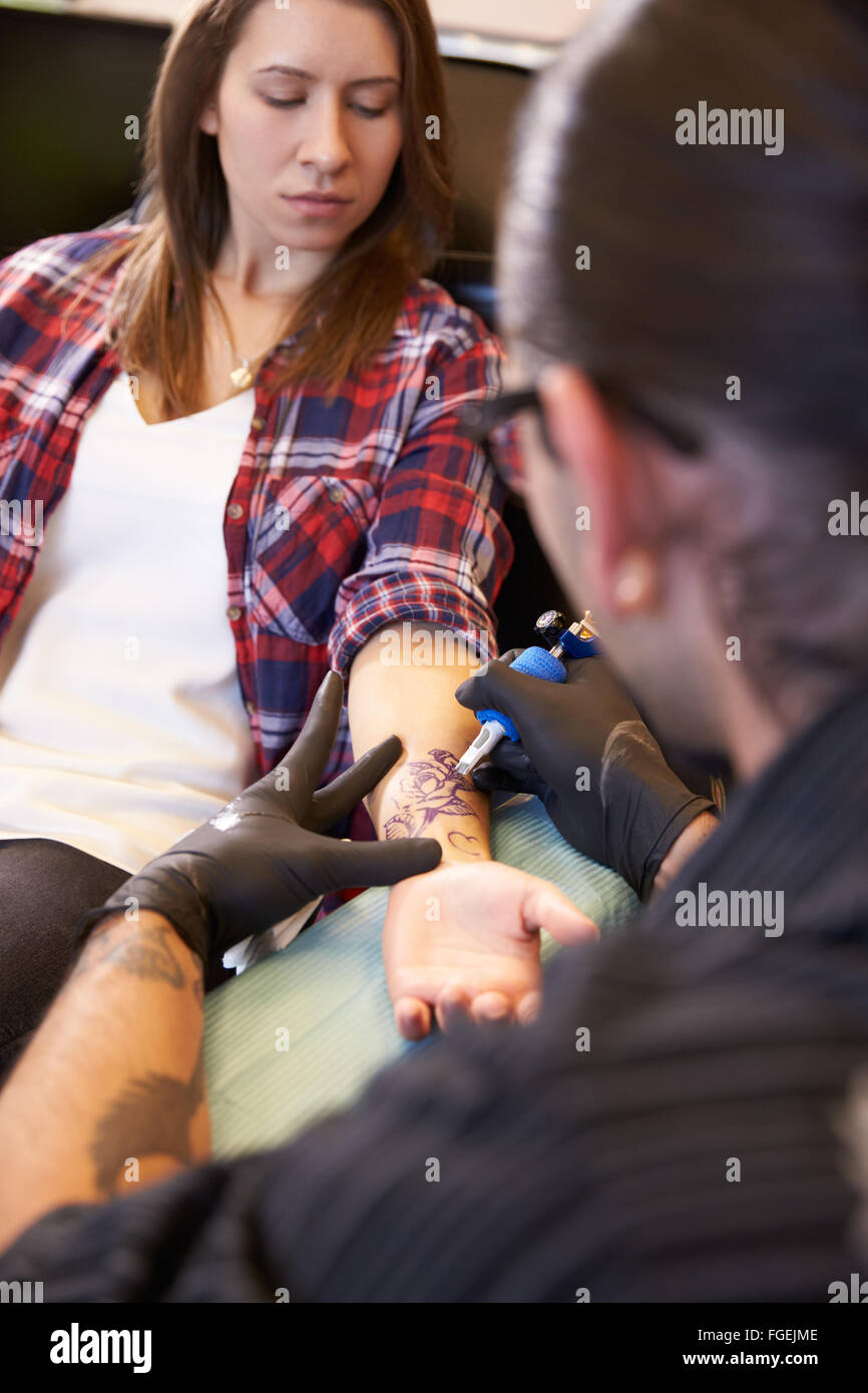 Woman Sitting in Chair ayant Tattoo sur le bras dans le salon Banque D'Images