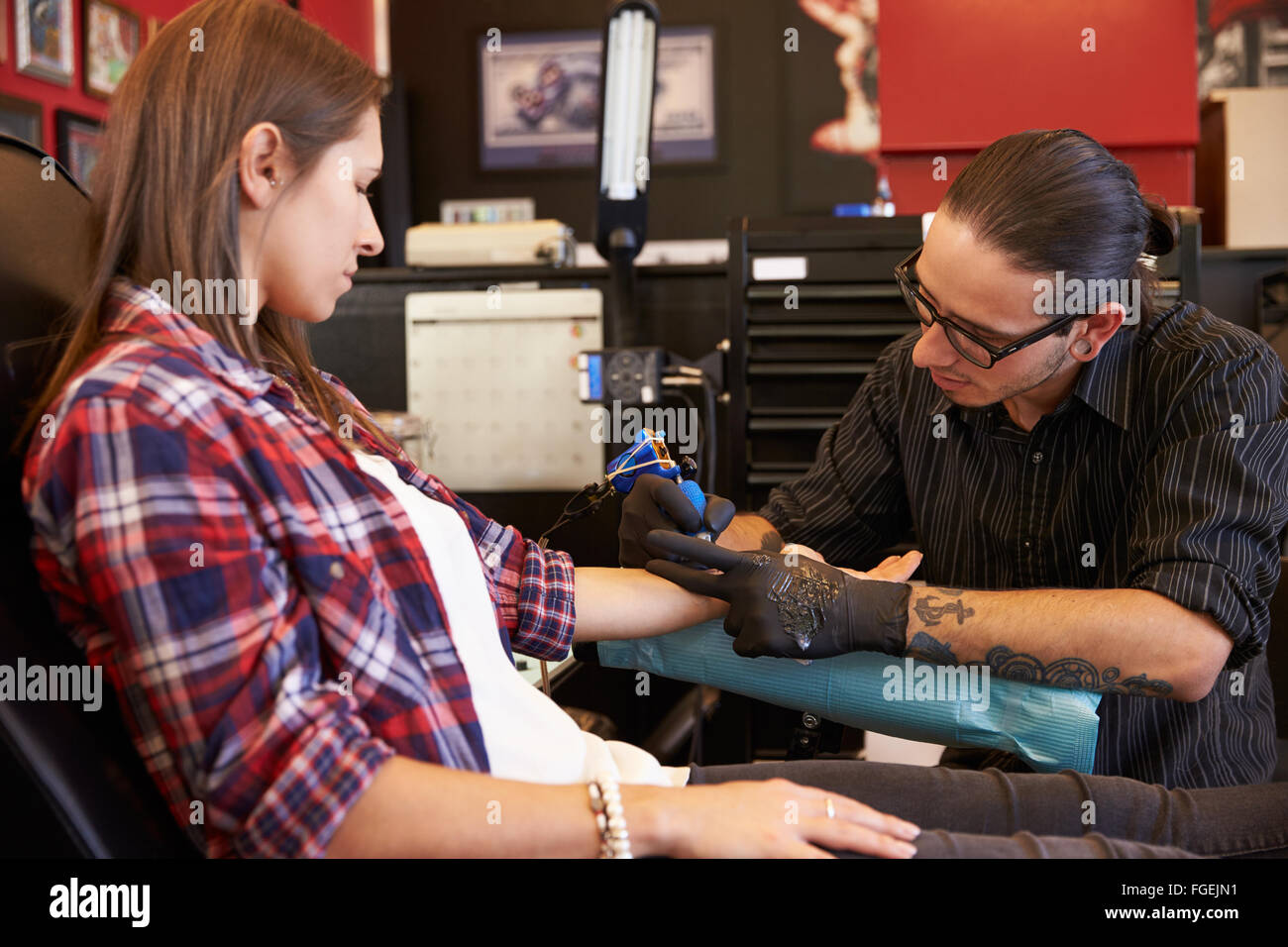 Woman Sitting in Chair ayant Tattoo sur le bras dans le salon Banque D'Images