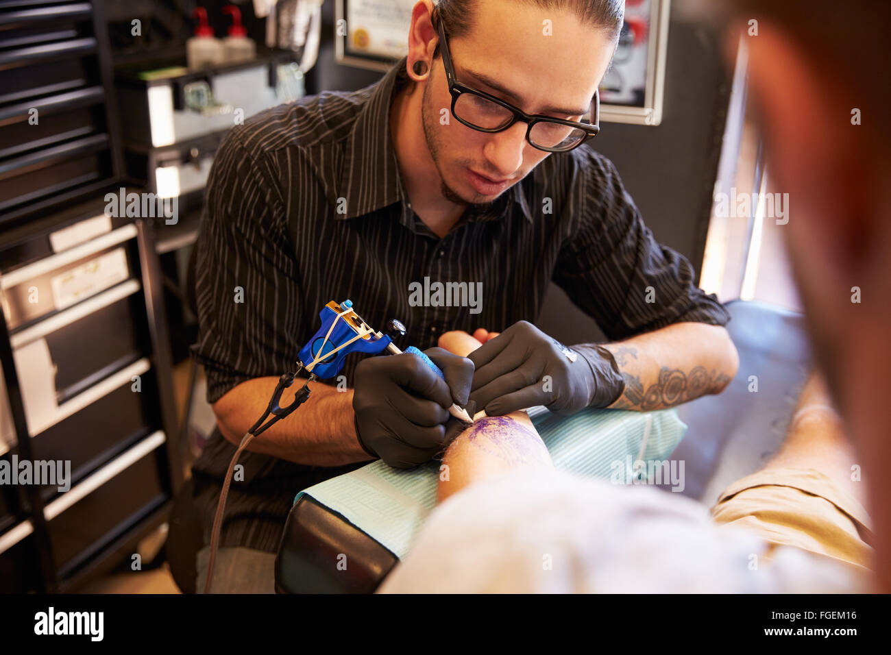 Le travail sur le design de l'artiste de tatouage pour les clients masculins Banque D'Images