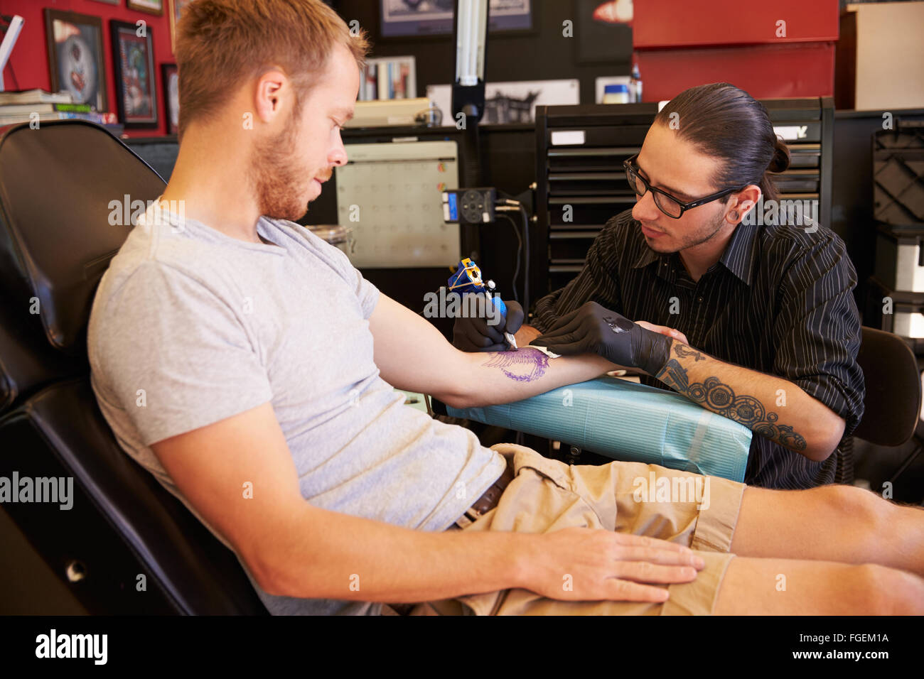 Man Sitting in Chair ayant Tattoo sur le bras dans le salon Banque D'Images