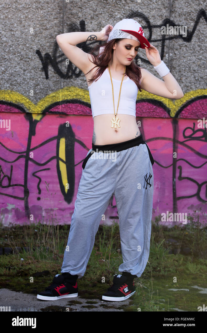 Modèle féminin en milieu urbain avec une chaîne en or skateboard survet et chapeau Banque D'Images