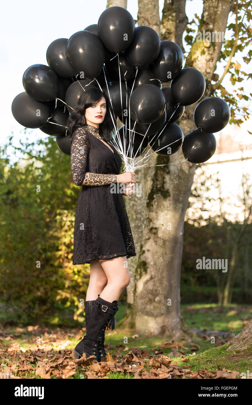 Jeune femme en robe noire posant avec ballo noir Banque D'Images