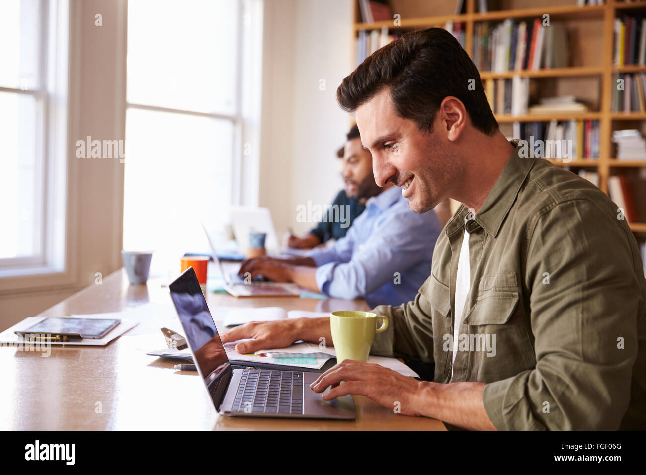 Businessman Using Laptop At Desk In Office Occupé Banque D'Images